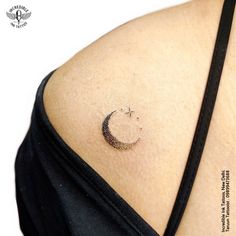 the back of a woman's shoulder with a small crescent tattoo on her left side