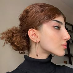 a close up of a person wearing large hoop earrings and a black turtle neck sweater