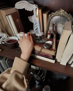 a person's hand reaching for an object on a table with books and candles