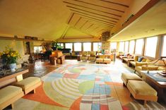 a living room filled with lots of furniture next to large windows and a painting on the wall