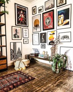 a room filled with lots of framed pictures on the wall next to a wooden floor