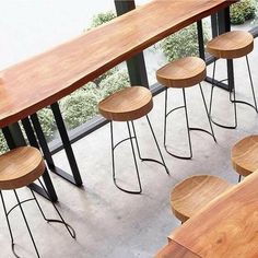 four wooden stools sitting next to each other on top of a cement floor in front of a window