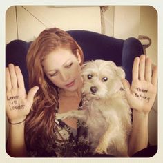 a woman sitting in a chair holding a dog and two hands with writing on them