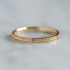 a gold wedding band on a white surface