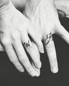 two people with matching tattoos on their hands holding each other's fingers and the word love written in cursive letters