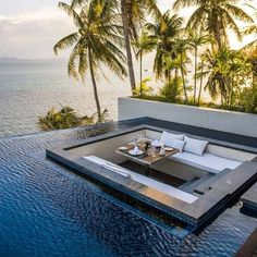 an outdoor living area with palm trees and water in the foreground, overlooking the ocean