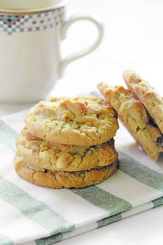 three cookies sitting on top of a white and green towel next to a coffee cup