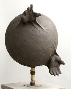 a sculpture is shown on top of a white pedestal with a gray ball and wooden stick sticking out of it