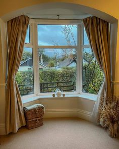 a corner window with drapes and curtains in front of a view of the trees outside