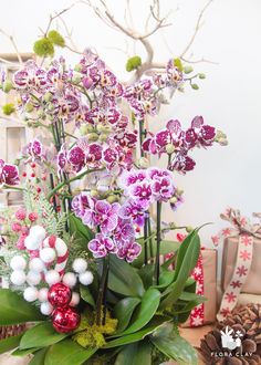 a vase filled with purple and white flowers on top of a table next to presents