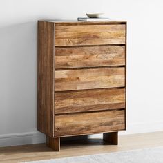 a wooden chest of drawers sitting on top of a hard wood floor next to a white wall