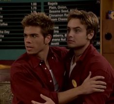 two young men hugging each other in front of a tv screen