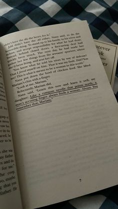 an open book sitting on top of a blue and white checkered table cloth next to two smaller books