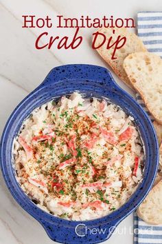 a blue bowl filled with crab dip next to two slices of bread