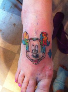 a child's foot with a mickey mouse tattoo on the top and bottom of it