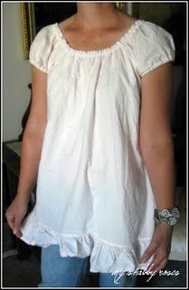 a woman standing in front of a mirror wearing a white shirt with ruffles