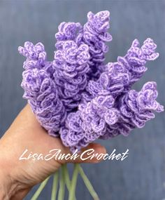 crocheted lavender flowers are being held by someone's hand