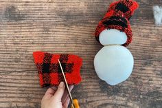 someone is making a snowman ornament out of woolen yarn and knitting needles