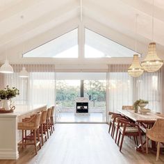 a large open kitchen with white walls and wooden flooring, along with a dining table set for eight