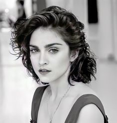 a black and white photo of a woman with curly hair, wearing a halter top