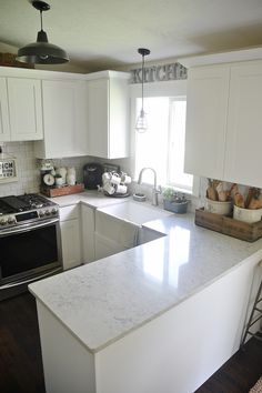 a kitchen with white cabinets and marble counter tops