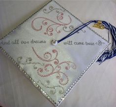 a white graduation cap with beaded designs and words on the front, along with a tassel