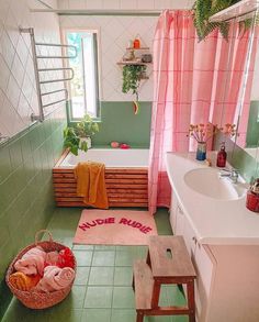 a bathroom with green tile and pink curtains