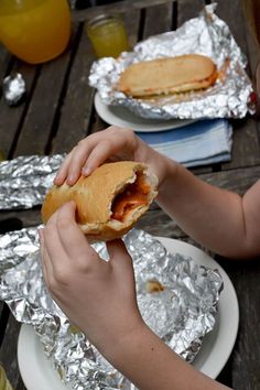 a person is eating a sandwich on aluminum foil