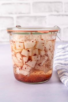 a glass jar filled with food sitting on top of a table next to a blue and white towel