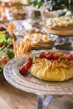 some food is sitting on a table with other plates and trays full of food