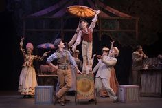 a group of people standing on top of a stage with umbrellas in the air