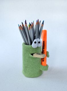 a green cup filled with pencils and an orange crayon