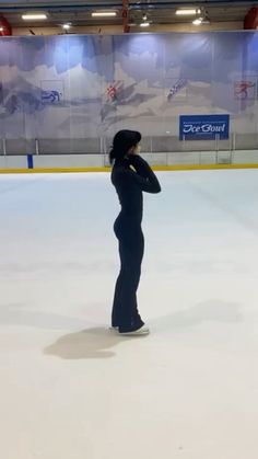 a woman standing on an ice rink with her arms behind her back and head in her hands