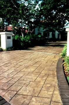 a brick walkway with trees and bushes in the background