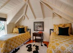 two beds in a room with yellow and white bedding on the walls, black and white rug