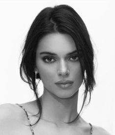 a black and white photo of a woman with necklaces on her neck looking at the camera