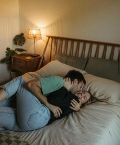 a man and woman laying on top of a bed next to each other in a bedroom