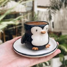 a penguin cup sitting on top of a saucer