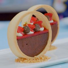 two desserts with chocolate and strawberries are on a white plate in the shape of circles