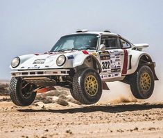 a white car driving on top of dirt covered ground