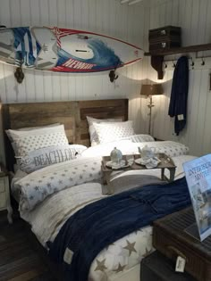 a bed room with a neatly made bed and a surfboard on the wall above it