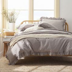 a bed sitting next to a window in a bedroom under a white and brown checkered comforter