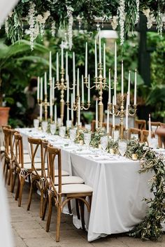 a long table is set up with candles and greenery for an outdoor wedding reception