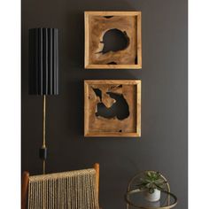 two framed pictures on the wall next to a wicker chair and table with a lamp