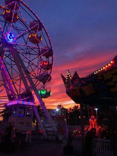 an amusement park at night with lights on the ferris wheel