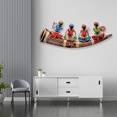 a wall mounted art piece depicting three people on a canoe with paddles in the foreground