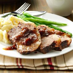 a white plate topped with meat, potatoes and green beans