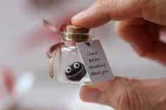 a hand holding a tiny glass bottle with a black ball in it and a tag that says i want bean birthday about you