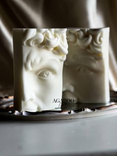 two soaps with faces on them sitting next to each other in front of a cloth