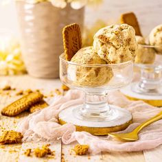 three scoops of ice cream in a glass bowl with cookies and graham crackers on the side